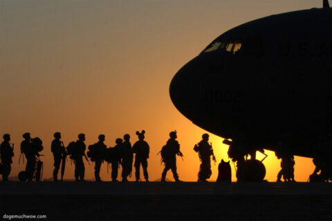 Soldier Mickey in line to get in a military plane. Sun set in the background, only silhouettes visible. Wow.